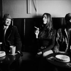 Black and white photograph of three people in a bar