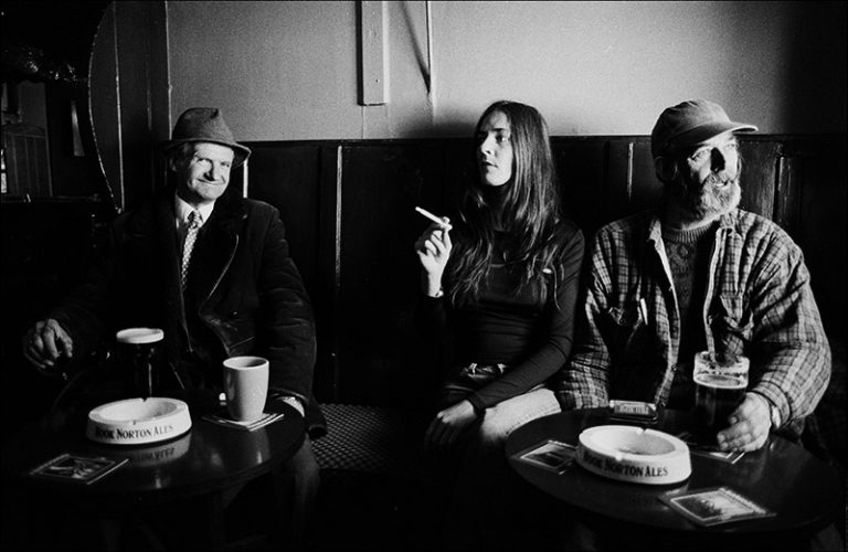 Black and white photograph of three people in a bar