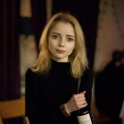 Photograph of a young girl clutching a bottle in a bar.