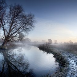 An early morning winter photograph of the river Bure Norfolk with some snow on the river banks.