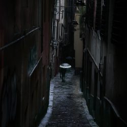 Photograph of a man with an umbrella in the rain in Genoa.