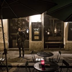 A colour photograph of an Italian having a cigarette in the street.