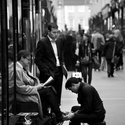 black and white photograph of a shoeshine at work in London.