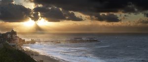 Colour photograph of a gathering storm near Cromer pier.