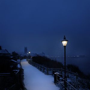 Colour photograph of snowfall on Cromer with lamplight.