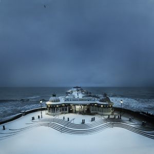 Colour photograph snowfall on Cromer pier before dawn.