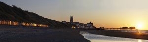 Colour photograph of the sunset at Cromer on the pier and beach huts