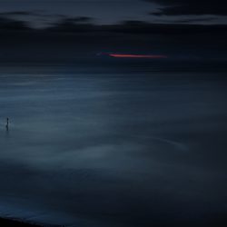 A dark moody photograph of the sea and the last rays of the setting sun.