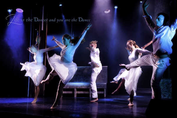 Dancers in white at the height of their dance. The title makes sense of their movement.