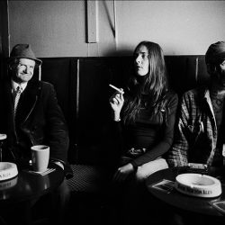 Black and white photograph of three people in a bar, it looks like the conversation may have become difficult.