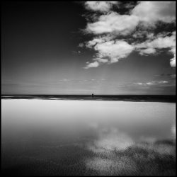 Black and white photograph of clouds reflected in pools of water on Holkham sands Norfolk.