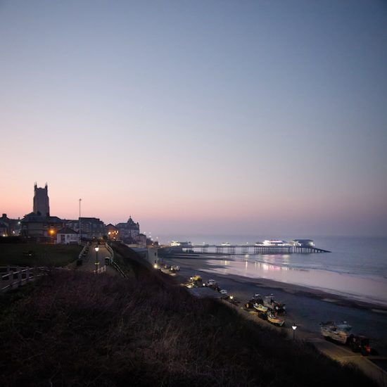 Moody evening image of Cromer in lamplight showing the fishing boats