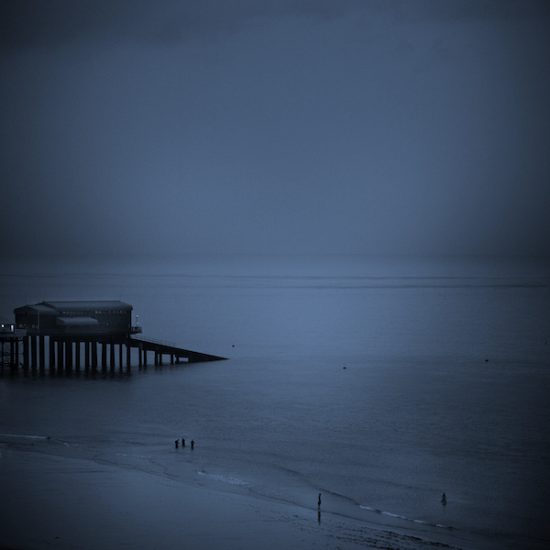 Dark moody image of Cromer beach and Lifeboat station and lost looking figures