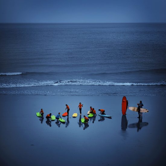 Photograph of surfboarders on Cromer beach in dramatic lighting