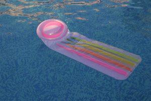 A photograph of a air bed in a swimming pool that looks like a condom.