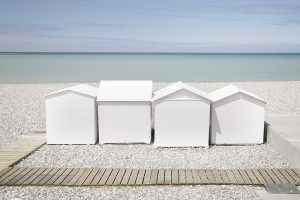 Photograph of white beach huts on the Normandy coast.